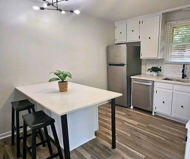 kitchen with sink, decorative backsplash, appliances with stainless steel finishes, white cabinetry, and a breakfast bar area