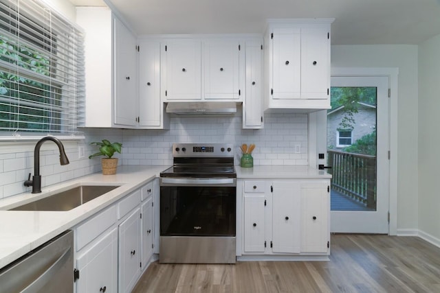 kitchen with tasteful backsplash, sink, white cabinets, and appliances with stainless steel finishes