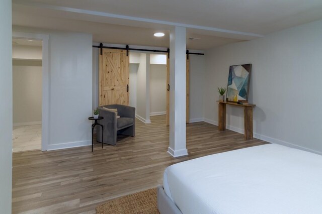 bedroom featuring a barn door and light wood-type flooring