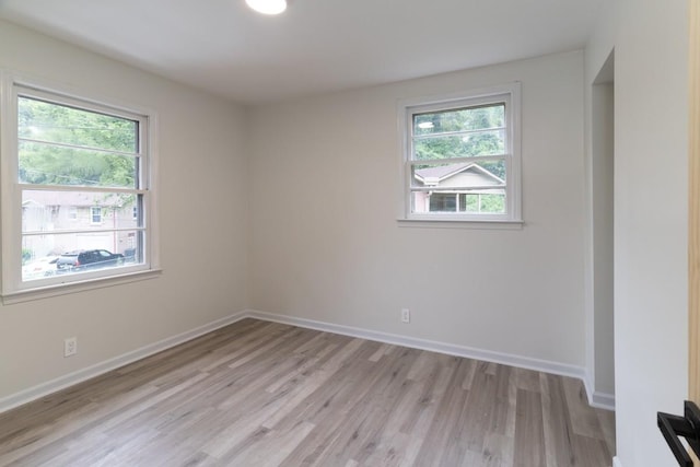 spare room with plenty of natural light and light hardwood / wood-style flooring