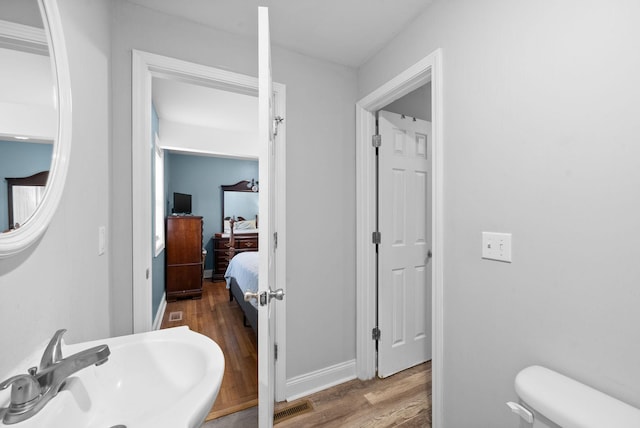 bathroom with toilet, wood-type flooring, and sink