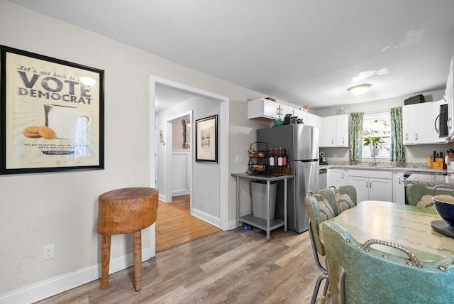 kitchen with sink, white cabinets, stainless steel appliances, and light wood-type flooring