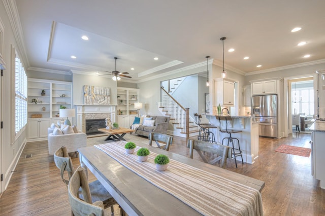 dining area featuring ceiling fan, a raised ceiling, and dark wood-type flooring