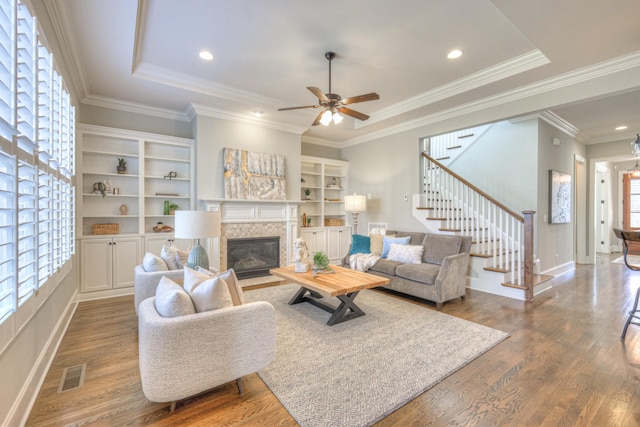 living room with a tiled fireplace, ceiling fan, hardwood / wood-style floors, and a healthy amount of sunlight