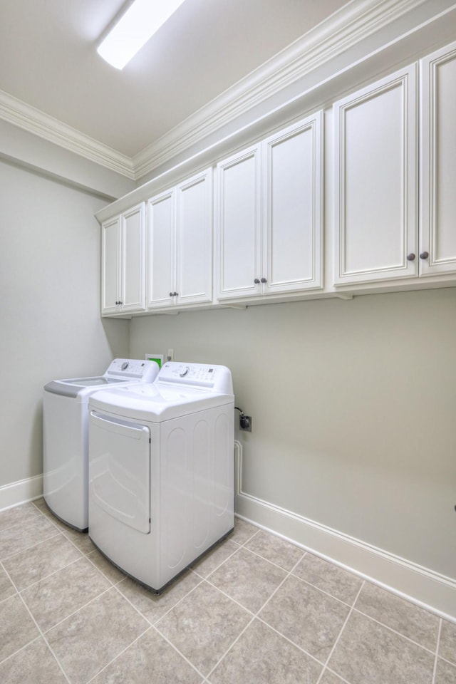 laundry area featuring washer and clothes dryer, cabinets, light tile patterned floors, and crown molding