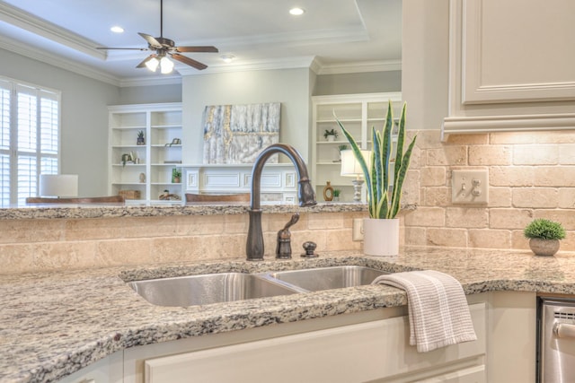 kitchen featuring light stone countertops, sink, white cabinets, and crown molding