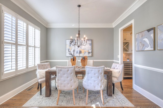 dining area with hardwood / wood-style flooring, crown molding, and an inviting chandelier