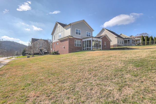 rear view of property featuring a yard and a sunroom