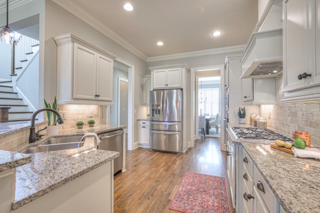 kitchen with sink, stainless steel appliances, light stone counters, pendant lighting, and custom exhaust hood