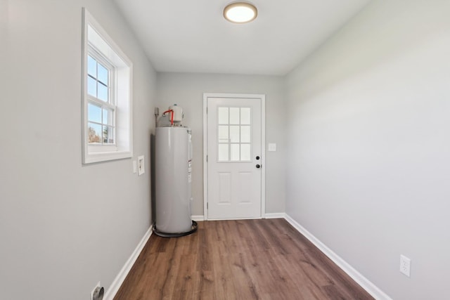 doorway to outside featuring baseboards, wood finished floors, and electric water heater