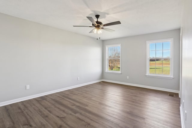 spare room with ceiling fan, dark wood finished floors, visible vents, and baseboards