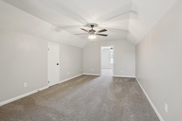 carpeted spare room featuring vaulted ceiling and baseboards