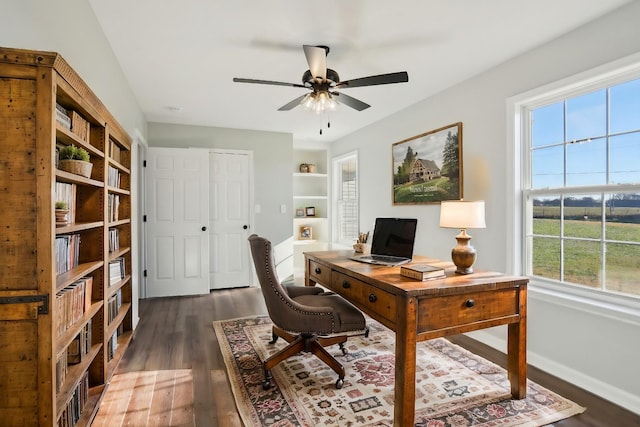 office space with dark wood-type flooring, baseboards, ceiling fan, and built in features