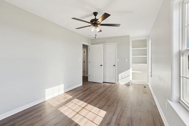 unfurnished bedroom with a ceiling fan, wood finished floors, visible vents, and baseboards