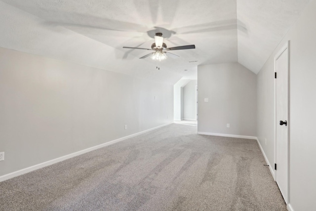 additional living space with carpet, a ceiling fan, vaulted ceiling, a textured ceiling, and baseboards