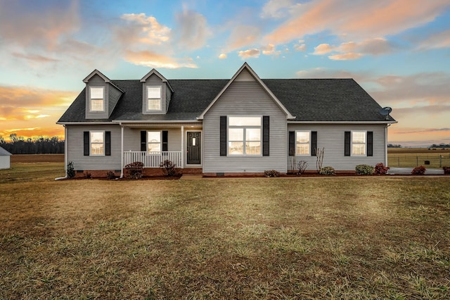 cape cod home featuring a yard and covered porch