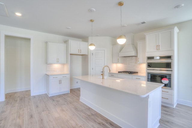 kitchen featuring custom exhaust hood, white cabinetry, sink, and stainless steel appliances