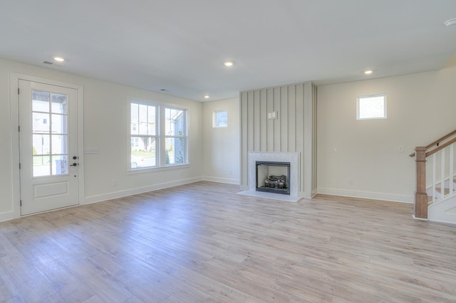 unfurnished living room with a large fireplace, plenty of natural light, and light hardwood / wood-style floors