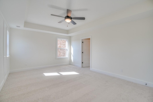 carpeted empty room featuring a raised ceiling and ceiling fan