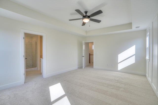 carpeted spare room with a tray ceiling and ceiling fan