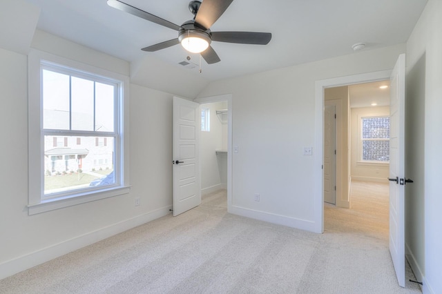 unfurnished bedroom featuring vaulted ceiling, ceiling fan, light carpet, and a spacious closet