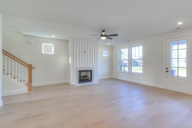 unfurnished living room featuring a fireplace, light wood-type flooring, and ceiling fan