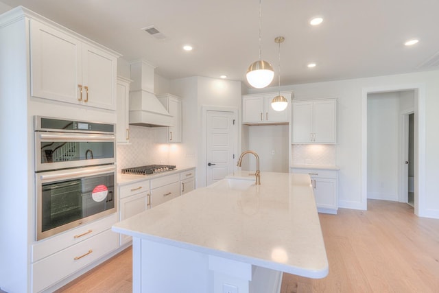 kitchen with white cabinetry, a kitchen island with sink, sink, and stainless steel appliances