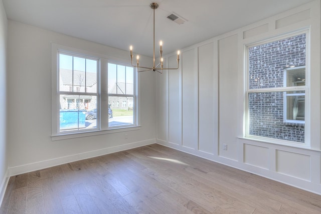 unfurnished dining area with light hardwood / wood-style floors and a notable chandelier