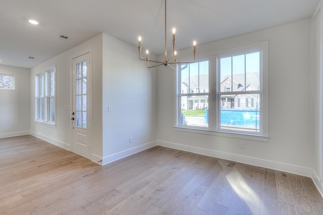 unfurnished dining area featuring light hardwood / wood-style floors and a notable chandelier