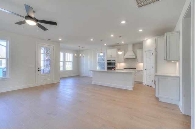 kitchen featuring pendant lighting, a center island, white cabinets, decorative backsplash, and custom range hood