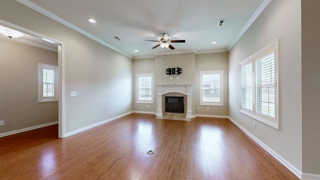 unfurnished living room featuring a fireplace, hardwood / wood-style floors, ceiling fan, and crown molding