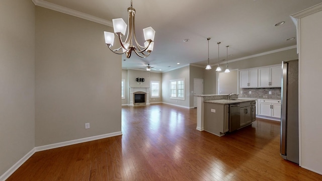 kitchen with a center island with sink, sink, decorative backsplash, decorative light fixtures, and stainless steel appliances