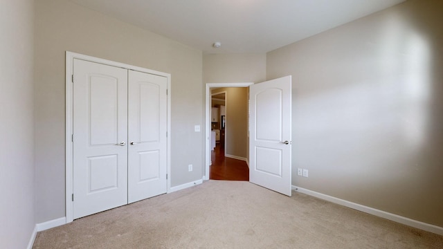 unfurnished bedroom with light carpet and a closet