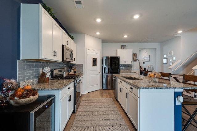 kitchen with white cabinets, sink, an island with sink, and stainless steel appliances