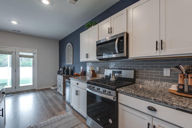 kitchen featuring white cabinets, dark stone countertops, appliances with stainless steel finishes, and tasteful backsplash