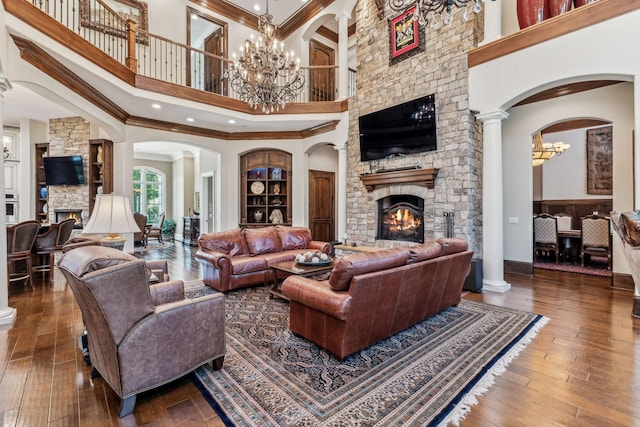 living room with a high ceiling, crown molding, a fireplace, a notable chandelier, and wood-type flooring