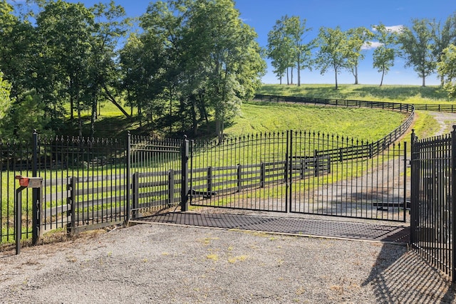 view of gate featuring a rural view and a lawn