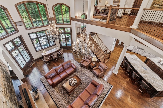 living room with decorative columns, plenty of natural light, a high ceiling, and hardwood / wood-style flooring