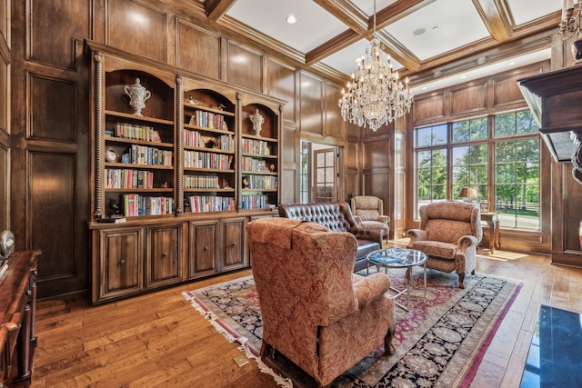 sitting room with an inviting chandelier, coffered ceiling, wooden walls, beamed ceiling, and light hardwood / wood-style floors