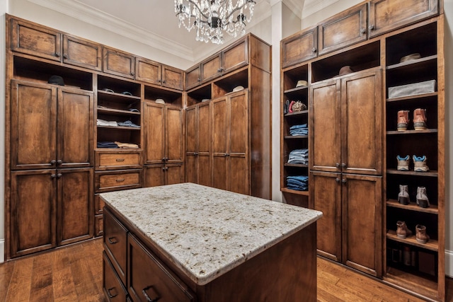 spacious closet with hardwood / wood-style floors and a notable chandelier