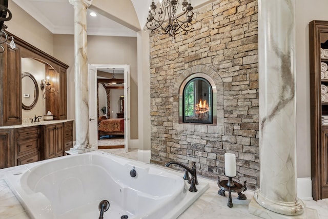 bathroom with vanity, decorative columns, crown molding, and tiled tub