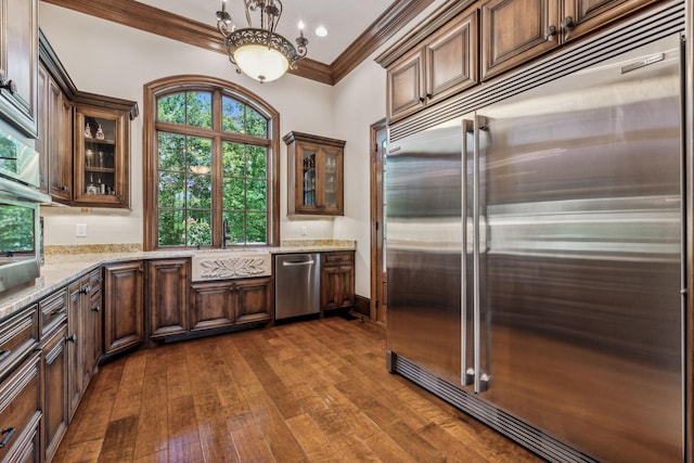 kitchen with light stone counters, dark hardwood / wood-style floors, crown molding, a chandelier, and appliances with stainless steel finishes