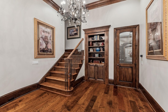 foyer with a chandelier, dark wood-type flooring, and ornamental molding