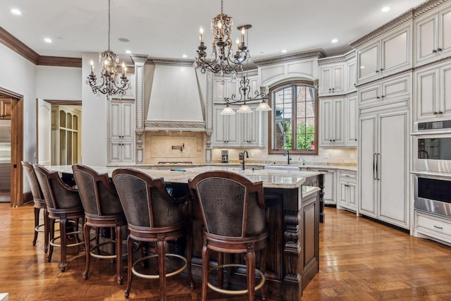 kitchen featuring pendant lighting, backsplash, light stone counters, and a kitchen island with sink