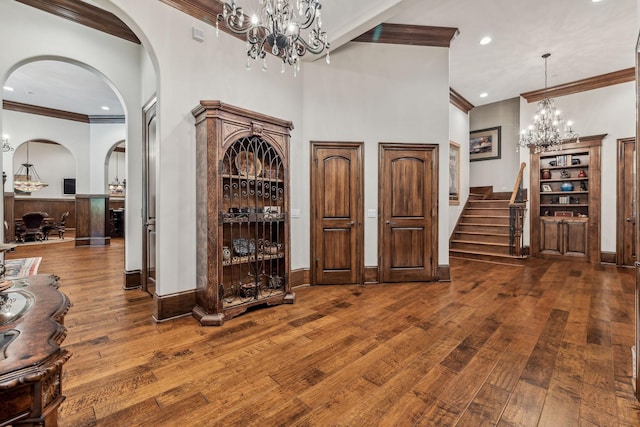 interior space featuring crown molding, dark hardwood / wood-style flooring, a high ceiling, and an inviting chandelier