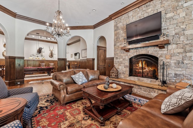 living room featuring a stone fireplace, hardwood / wood-style floors, a chandelier, and ornamental molding