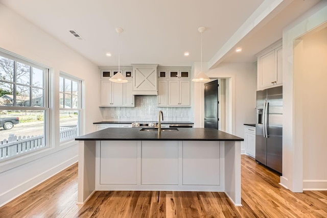 kitchen featuring white cabinets, pendant lighting, built in fridge, and sink