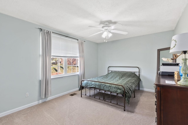 carpeted bedroom with ceiling fan and a textured ceiling