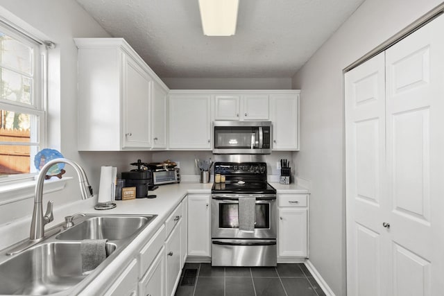 kitchen featuring white cabinetry, sink, stainless steel appliances, a textured ceiling, and dark tile patterned flooring