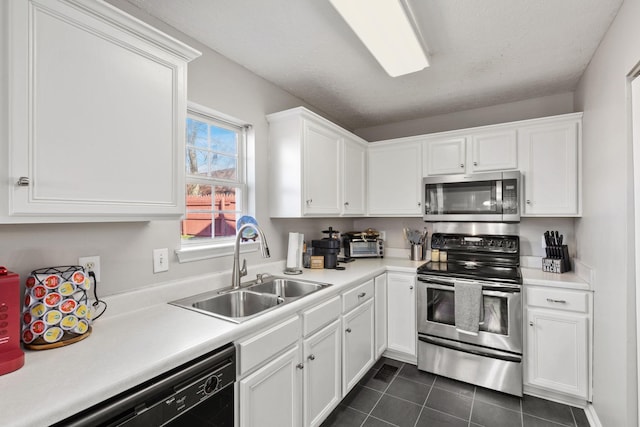 kitchen with white cabinets, appliances with stainless steel finishes, dark tile patterned floors, and sink